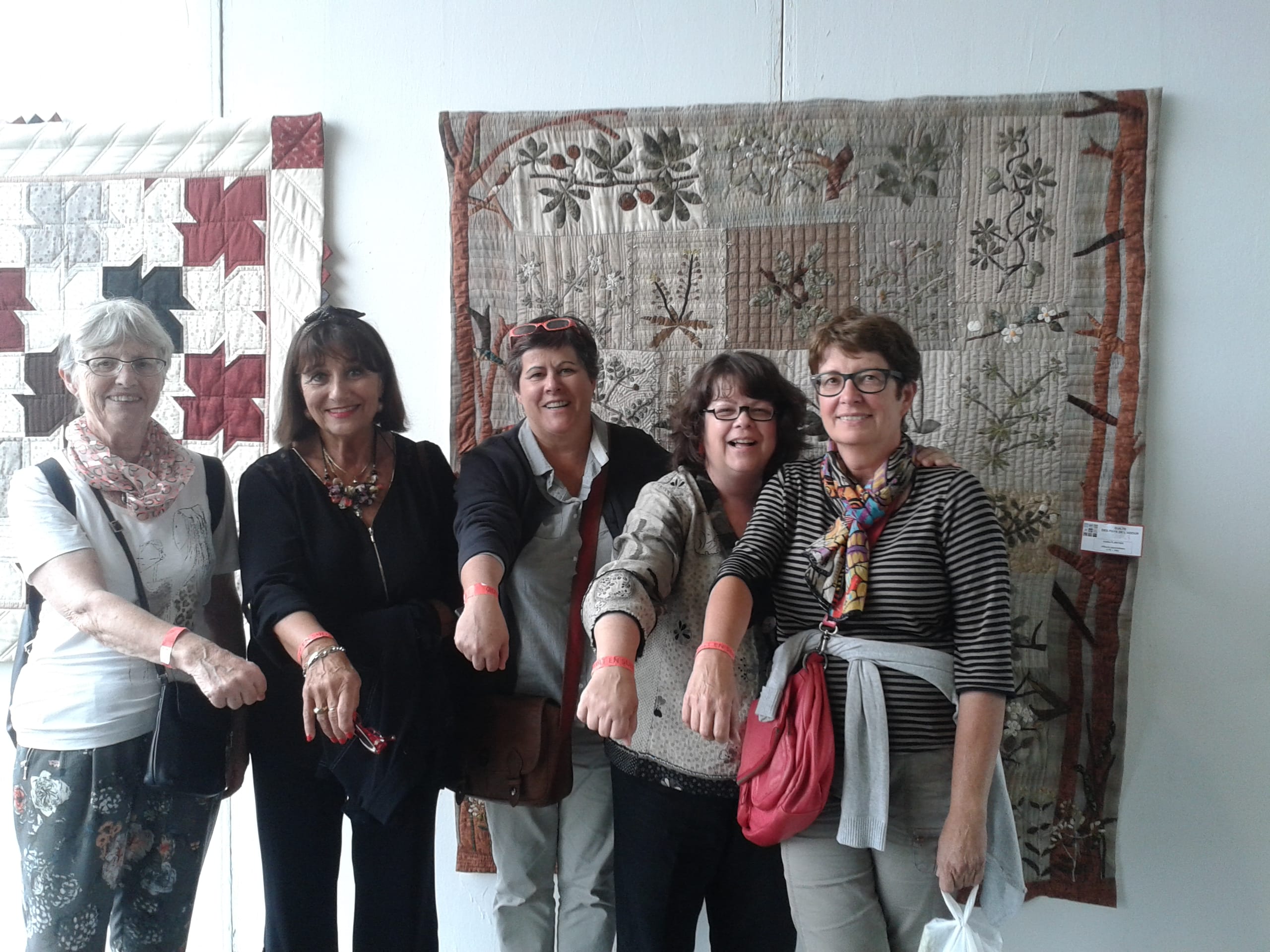 From Left to right, Jeannien, Marie Ange, Kathy, Me, and Catherine, in front of a beautiful quilt, flashing our orange arm bands.