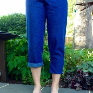 Denim capris with cuffed hem on right leg and more pegging on left leg. 